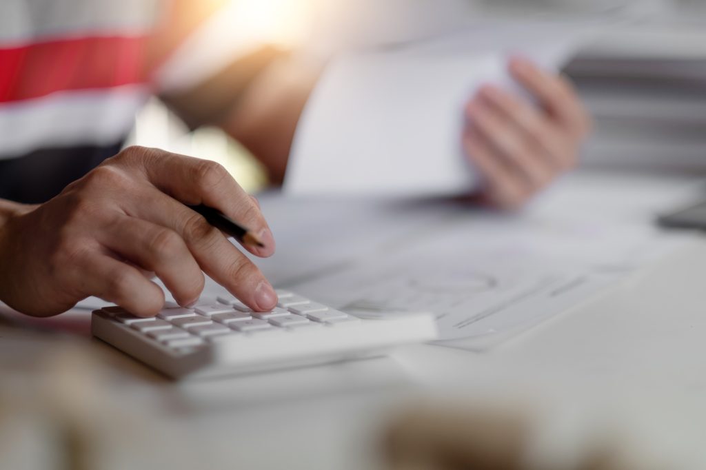 Close up man bookkeeping bills and payments with calculator at home.