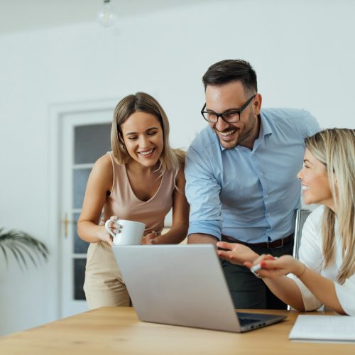 Portrait of a happy business team looking at laptop.